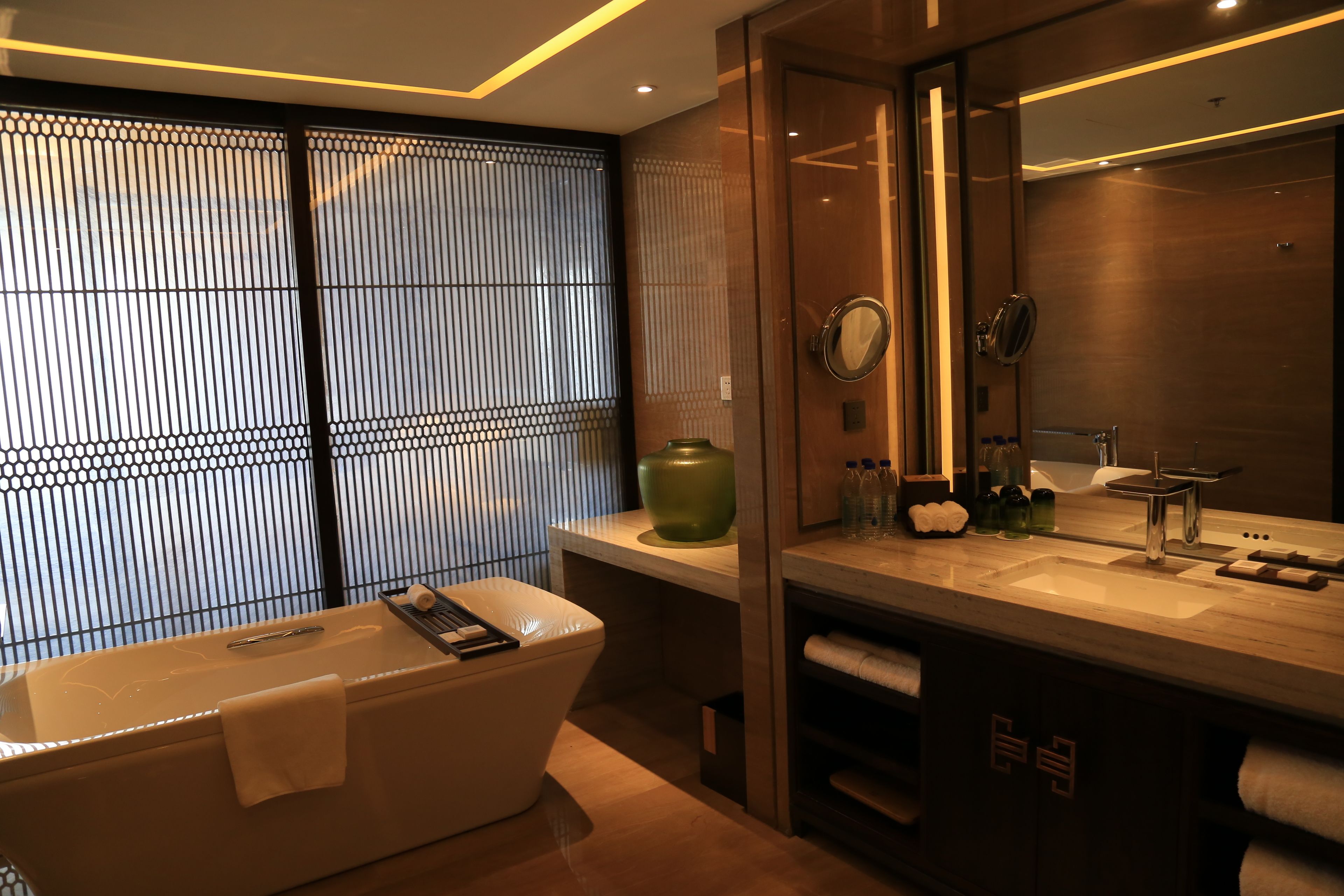 A modern bathroom with a freestanding bathtub, a large mirror, and a vanity with a sink.
