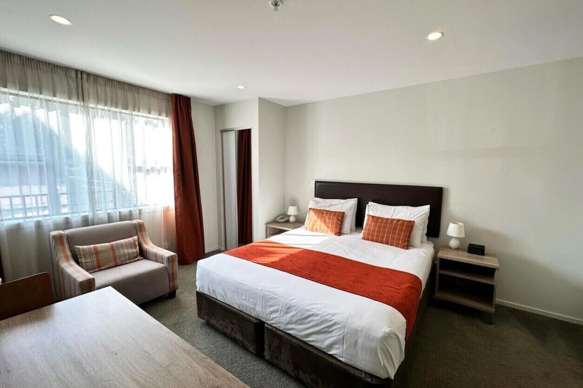 Een hotelkamer met een groot bed, een stoel, een bureau en een nachtkastje.