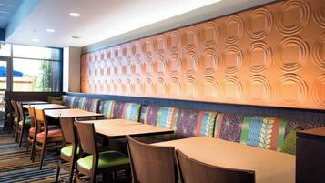 Un restaurante con cabinas y mesas, un muro con diseño y suelo alfombrado.