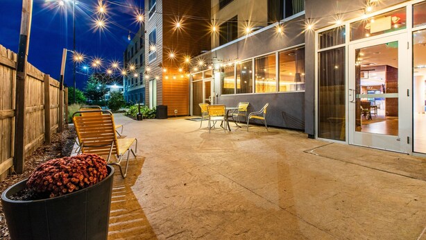 An outdoor patio area with a concrete floor, wooden fence, and string lights.
