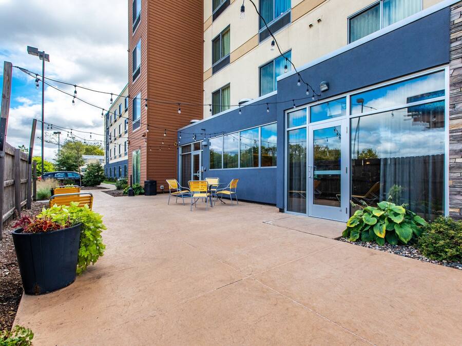 An outdoor patio area with a concrete floor, yellow chairs, and potted plants.