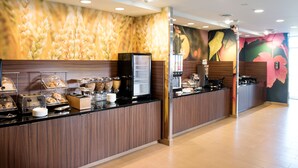 A breakfast bar with a wooden counter, a coffee machine, and a refrigerator.