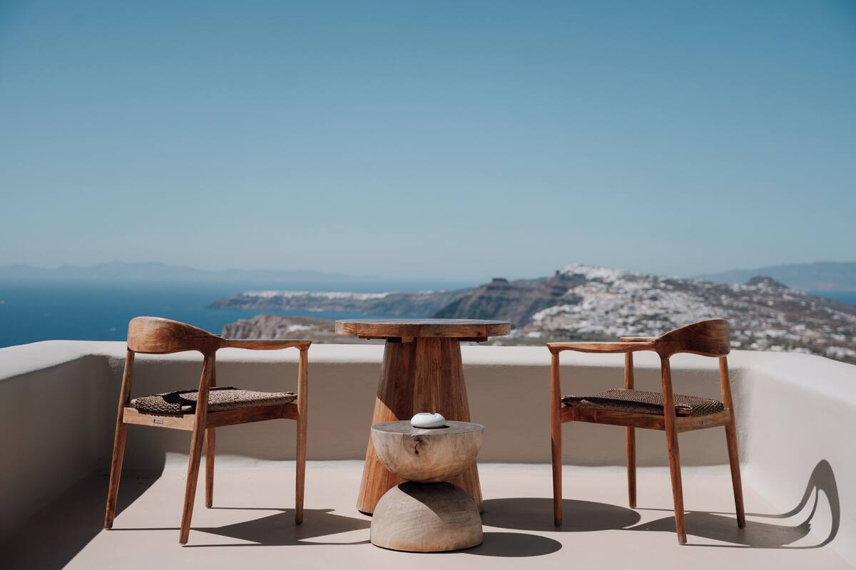 Ein Holztisch und zwei Stühle auf einem Balkon mit Blick auf eine Berglandschaft.