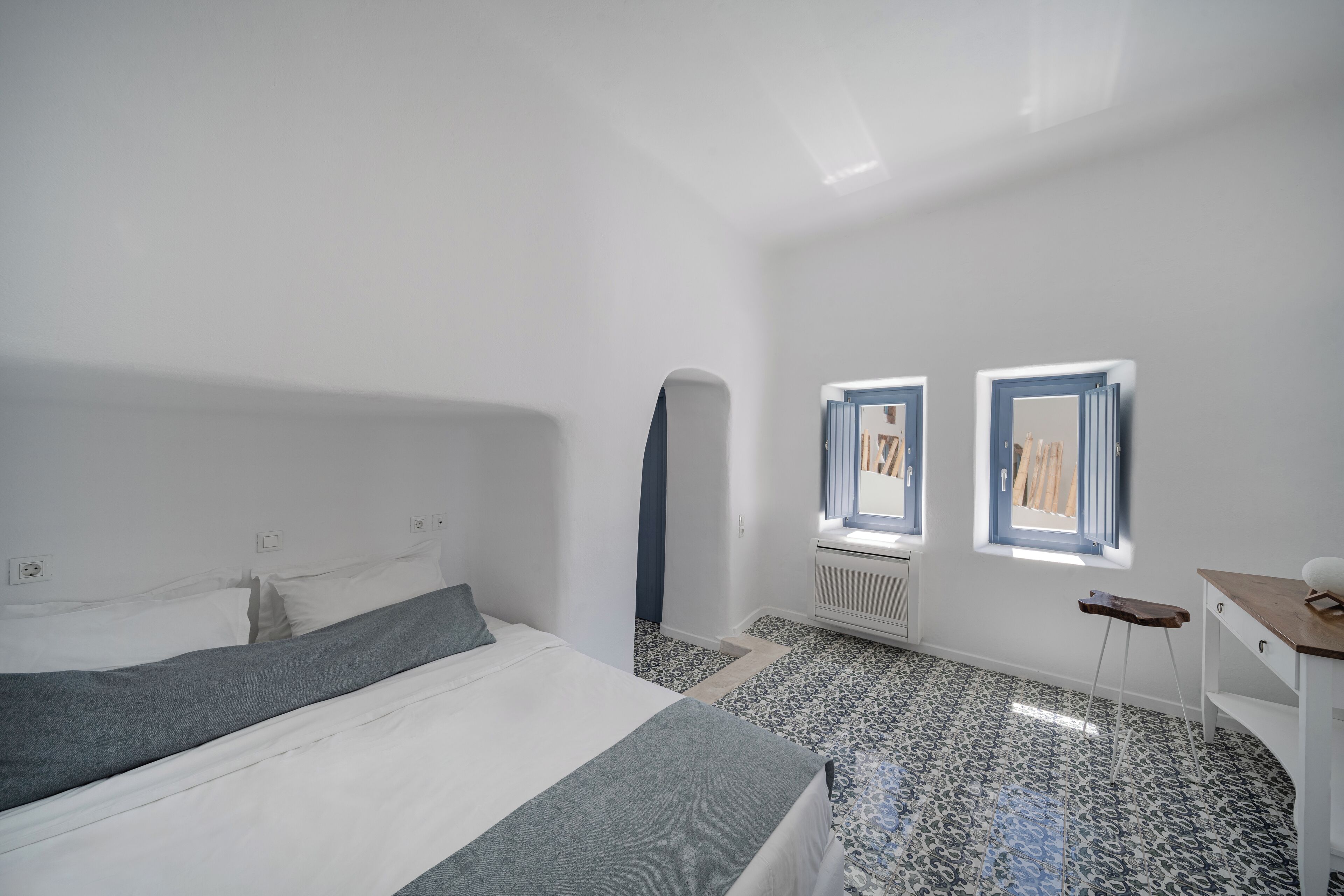 Une chambre à coucher avec un lit, un petit bureau et deux fenêtres.