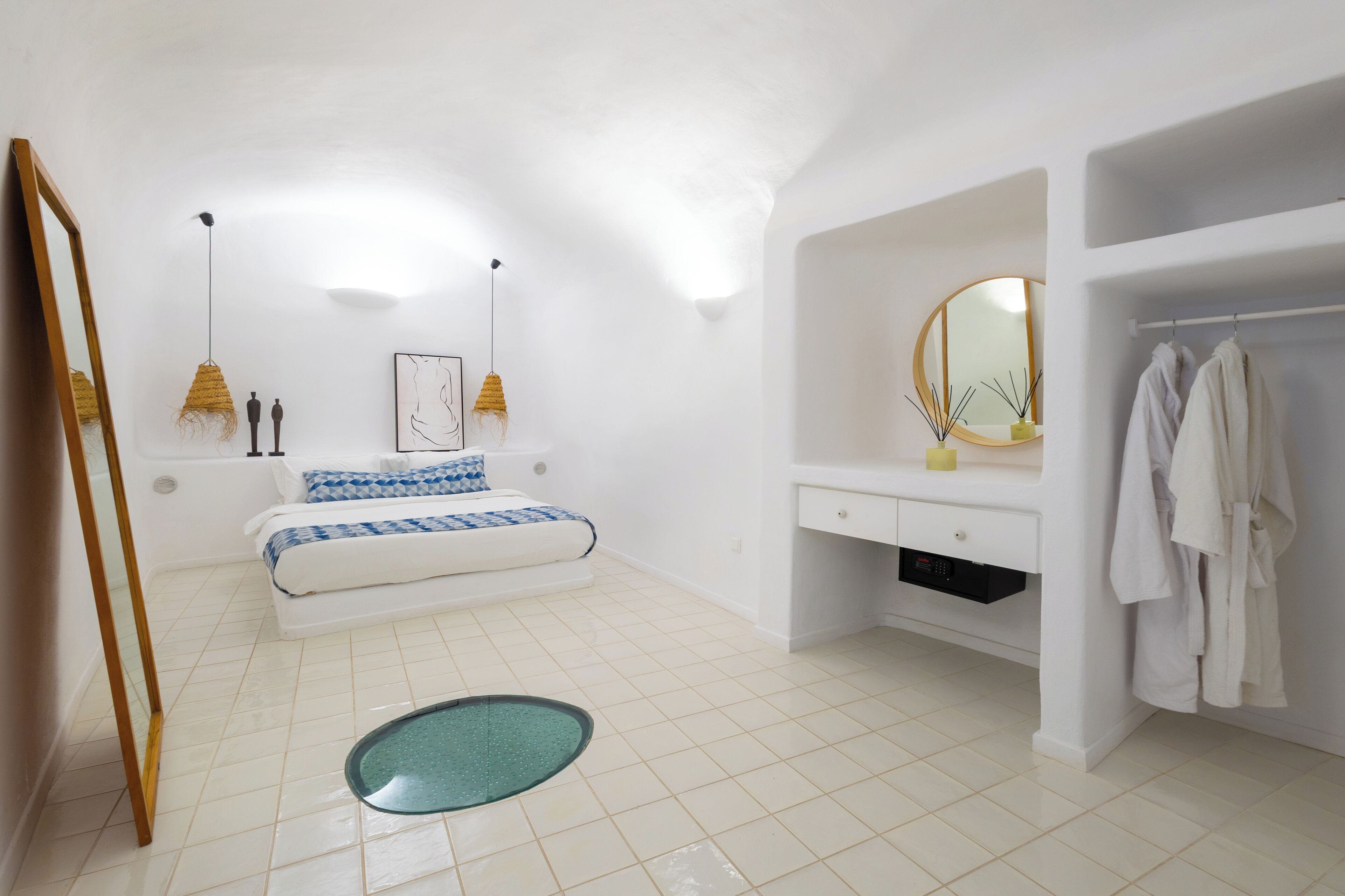 A modern bedroom with a bed, bedside lamps, a vanity with a mirror, and a bathtub.