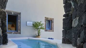 Un área de piscina con paredes de piedra y dos ventanas, una con una planta en su interior.