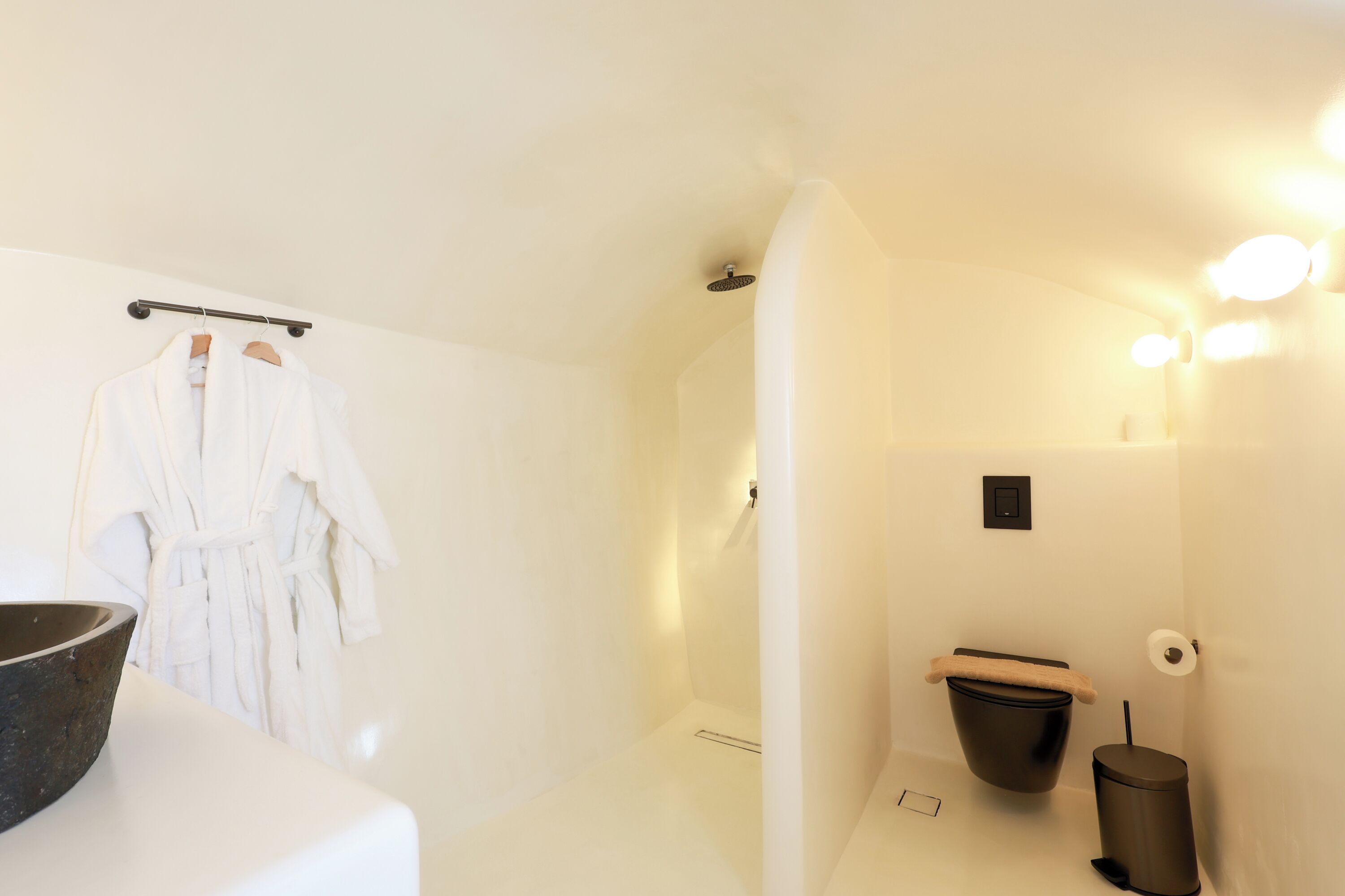 Ein modernes Badezimmer mit einer weißen Badewanne, einem schwarzen Mülleimer und einem weißen Handtuchhalter mit zwei Handtüchern.