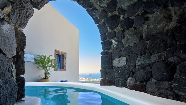 A stone-walled infinity pool with a clear view of the sea. - Luna Santorini Suites (Santorini)