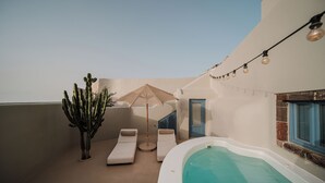 A rooftop pool area with lounge chairs, a cactus, and string lights. - Luna Santorini Suites (Santorini)