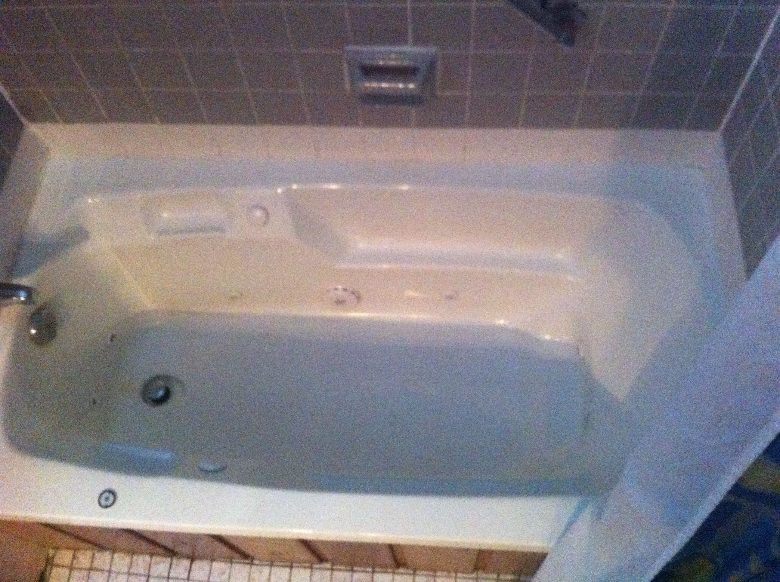 A standard bathtub with a faucet and a drain.