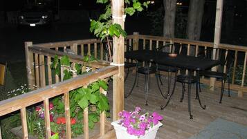 A wooden deck with a table and chairs, surrounded by a wooden railing and potted plants.