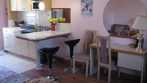 A kitchen with a dining area, a sink, a stove, and a chair.