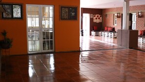 Amplia sala de estar con piso de baldosas pulidas, una escalera y un rincón de descanso con cojines.