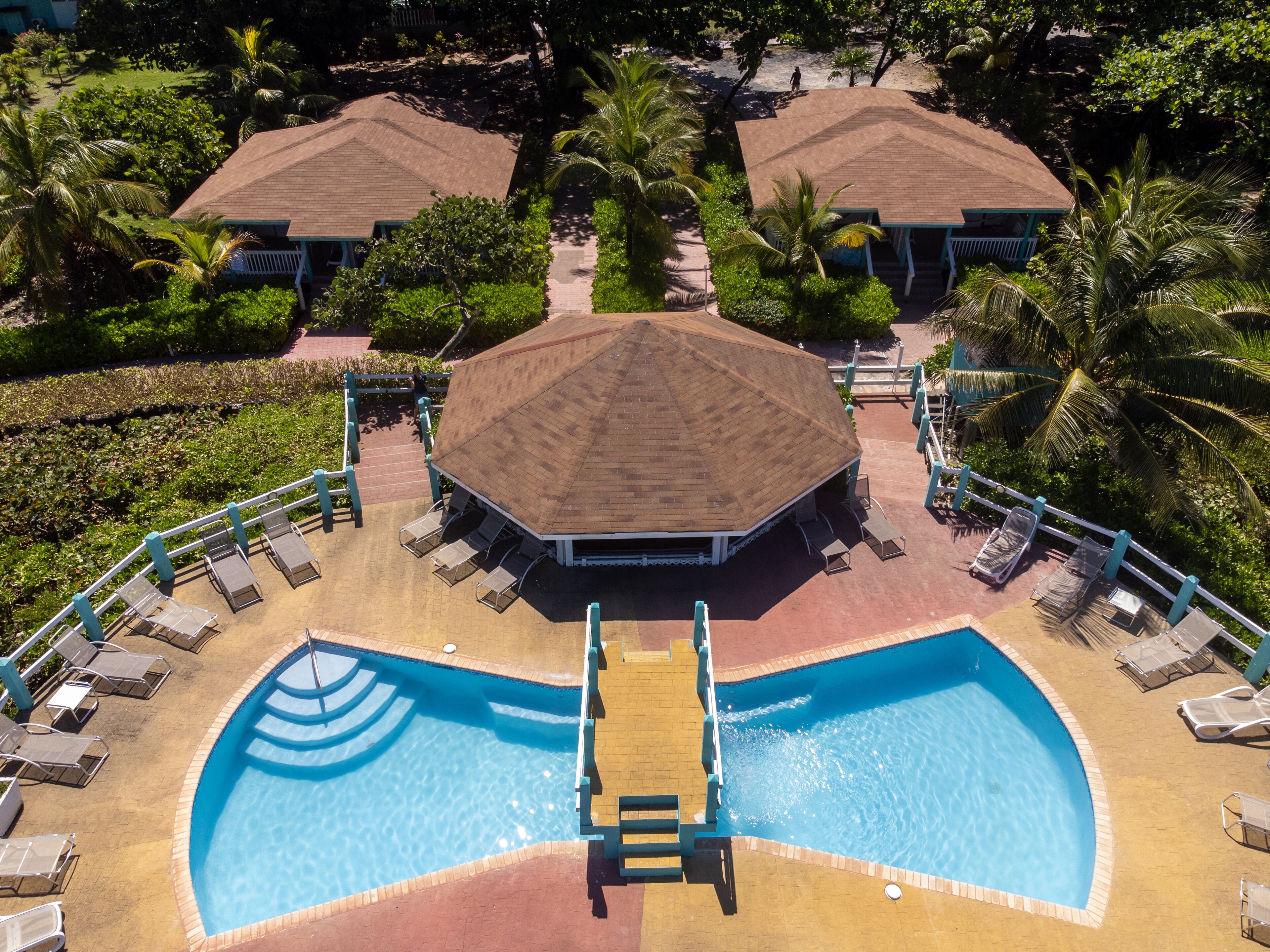Un resort con piscina central, sillas de descanso y un pabellón cubierto.