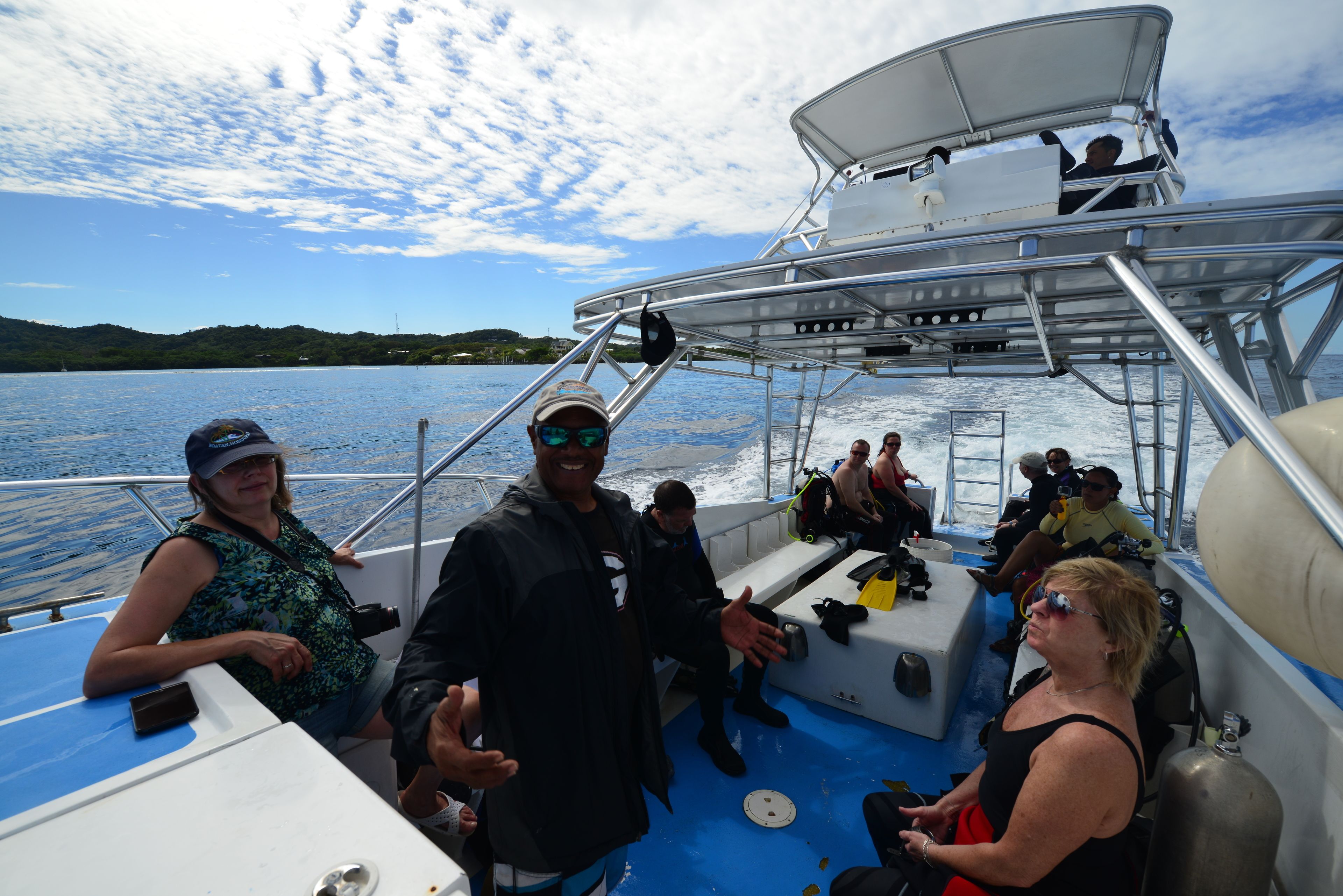 A boat with passengers, metal railings, and a water body in the background.