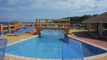 Relax by the pool surrounded by sun loungers and a scenic beach view.