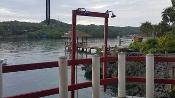 A dock with a red railing, a small gazebo, and a boat in the background.