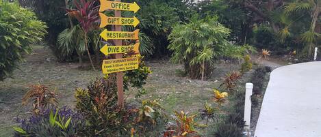 A signpost with directions to an office, gift shop, restaurant, and dive shop.