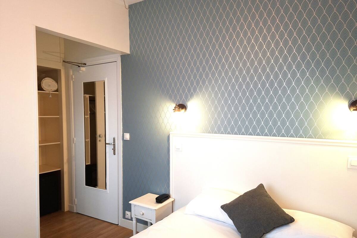 Une chambre à coucher comprenant un lit, une table de chevet, une commode, une armoire et une porte donnant sur un placard.