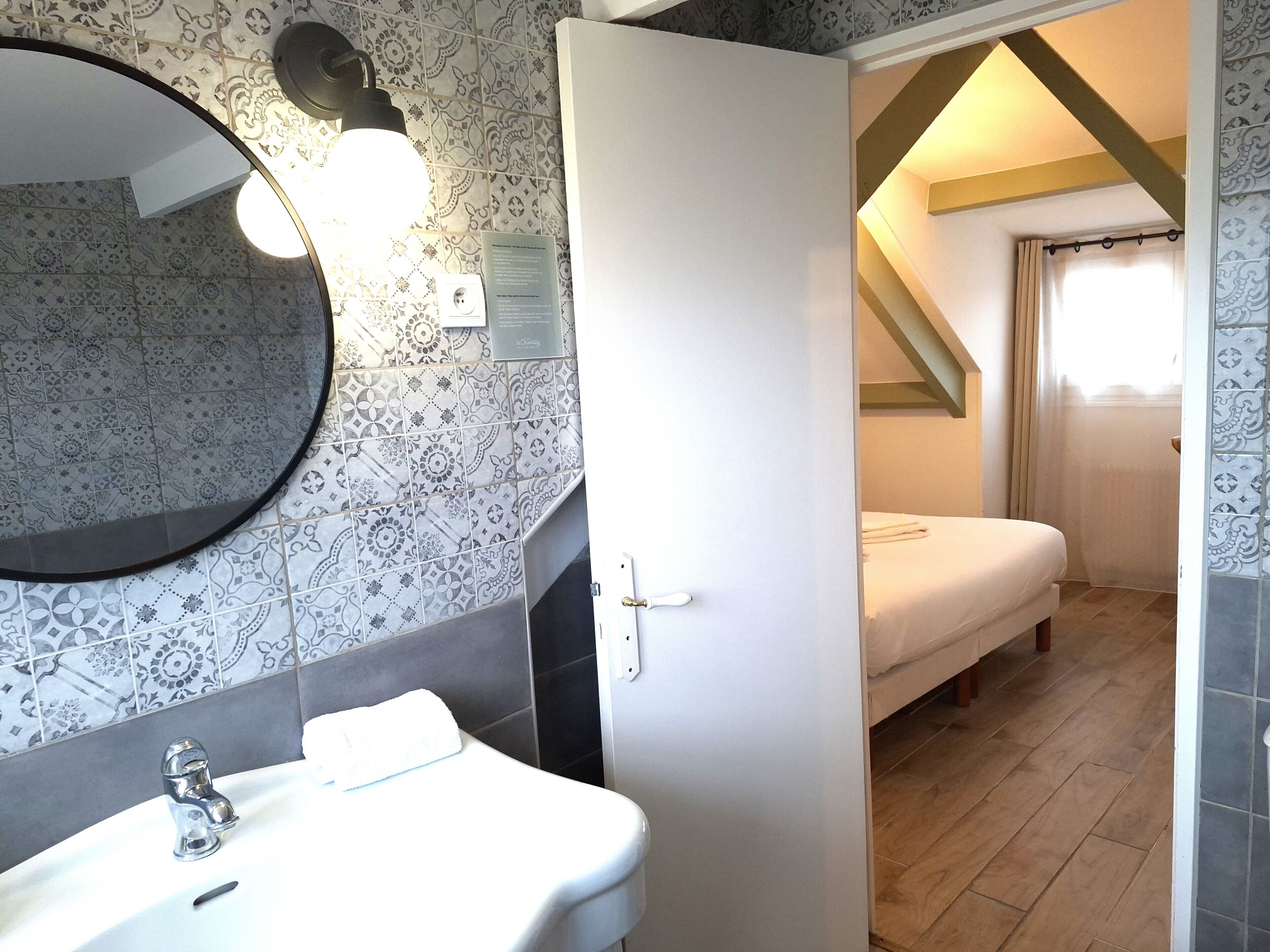 A bathroom with a sink, mirror, and patterned tiles.