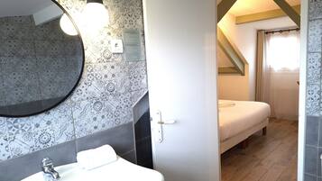 A bathroom with a sink, mirror, and patterned tiles.