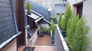 A narrow alleyway with a steep staircase leading to a building with a sloped roof and potted plants. - Hôtel Le Chantilly (Deauville)