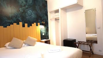 A hotel room with a bed, a wooden headboard, a wall-mounted mirror, and a wardrobe.
