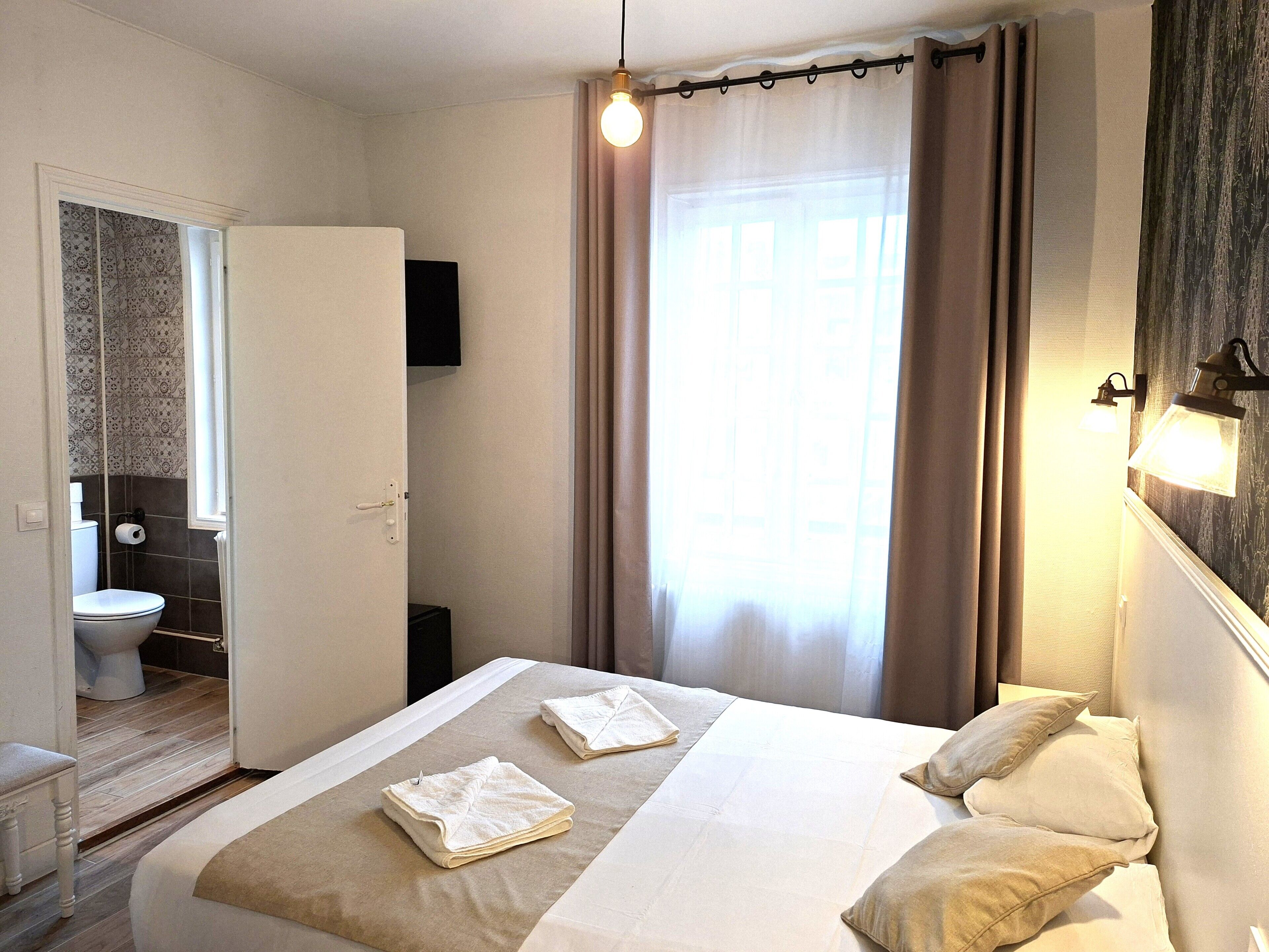 Una habitación de hotel con cama, baño y vistas al exterior.