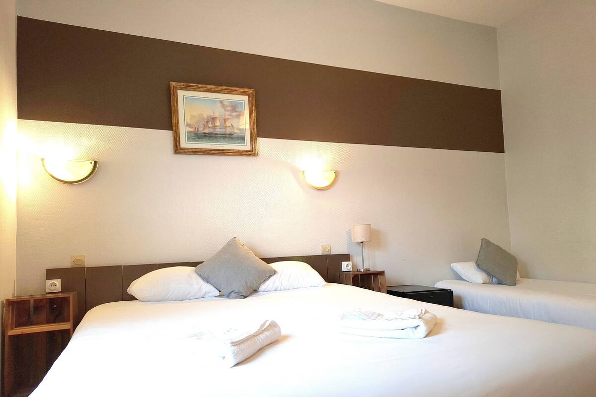 Une chambre d’hôtel avec deux lits, un tableau au mur et des lampes de chevet.