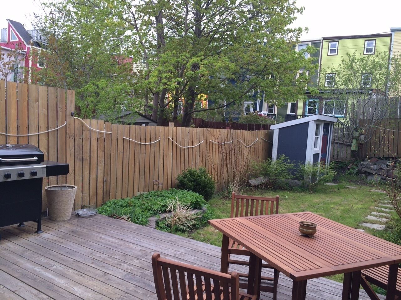 A wooden deck with a grill, a table, and chairs.