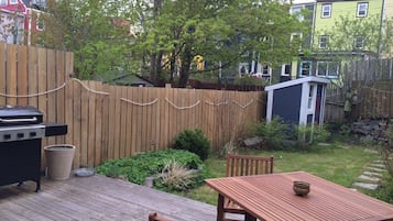 A wooden deck with a grill, a table, and chairs.