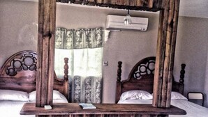 A rustic wooden mirror in a hotel room with two beds, each with a wooden headboard and a white mattress. - Hotel Taciana (Léogâne)