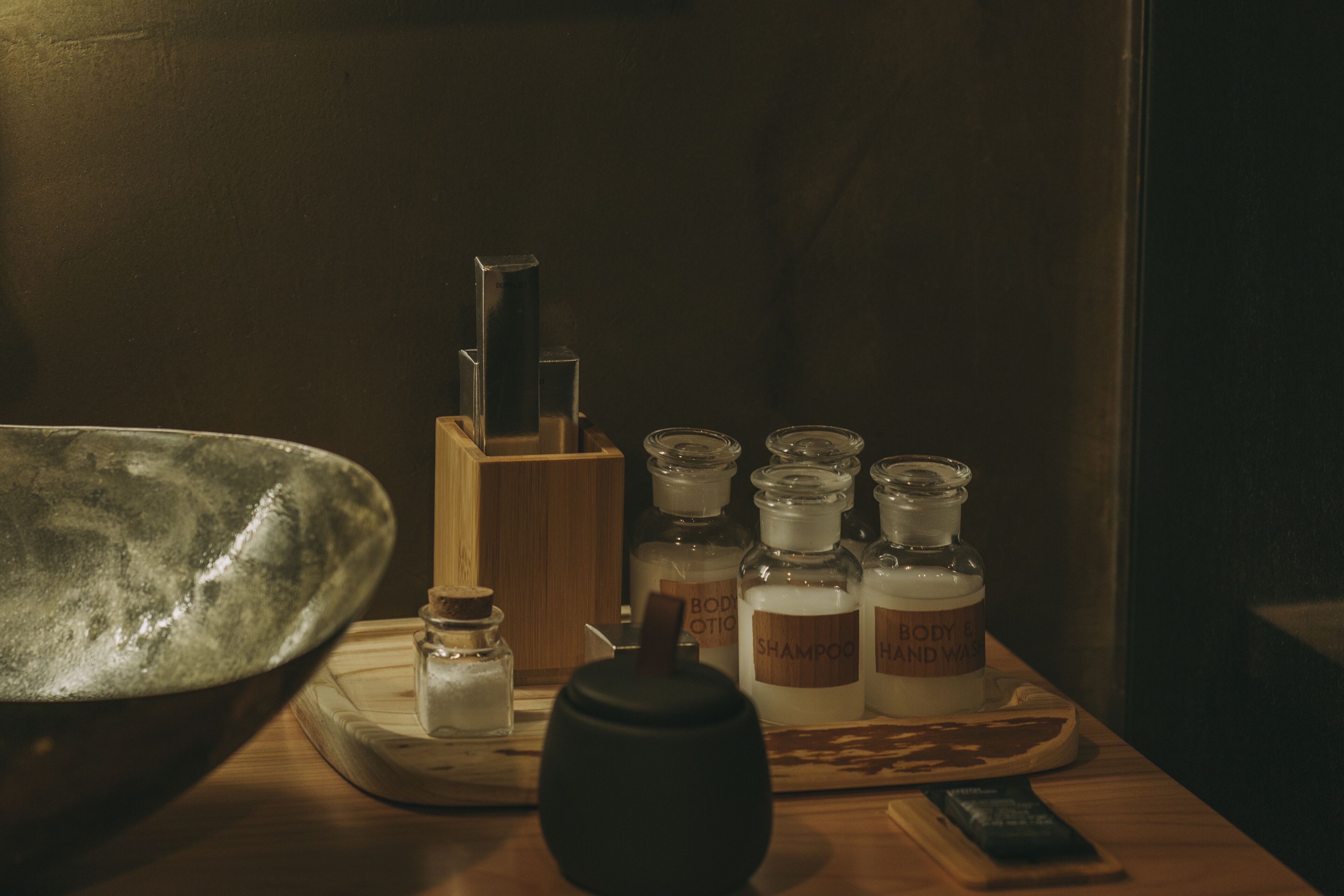 Une table en bois sur laquelle se trouvent divers articles de toilette, notamment des flacons et un bol en métal.
