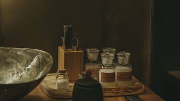 Une table en bois sur laquelle se trouvent divers articles de toilette, notamment des flacons et un bol en métal.