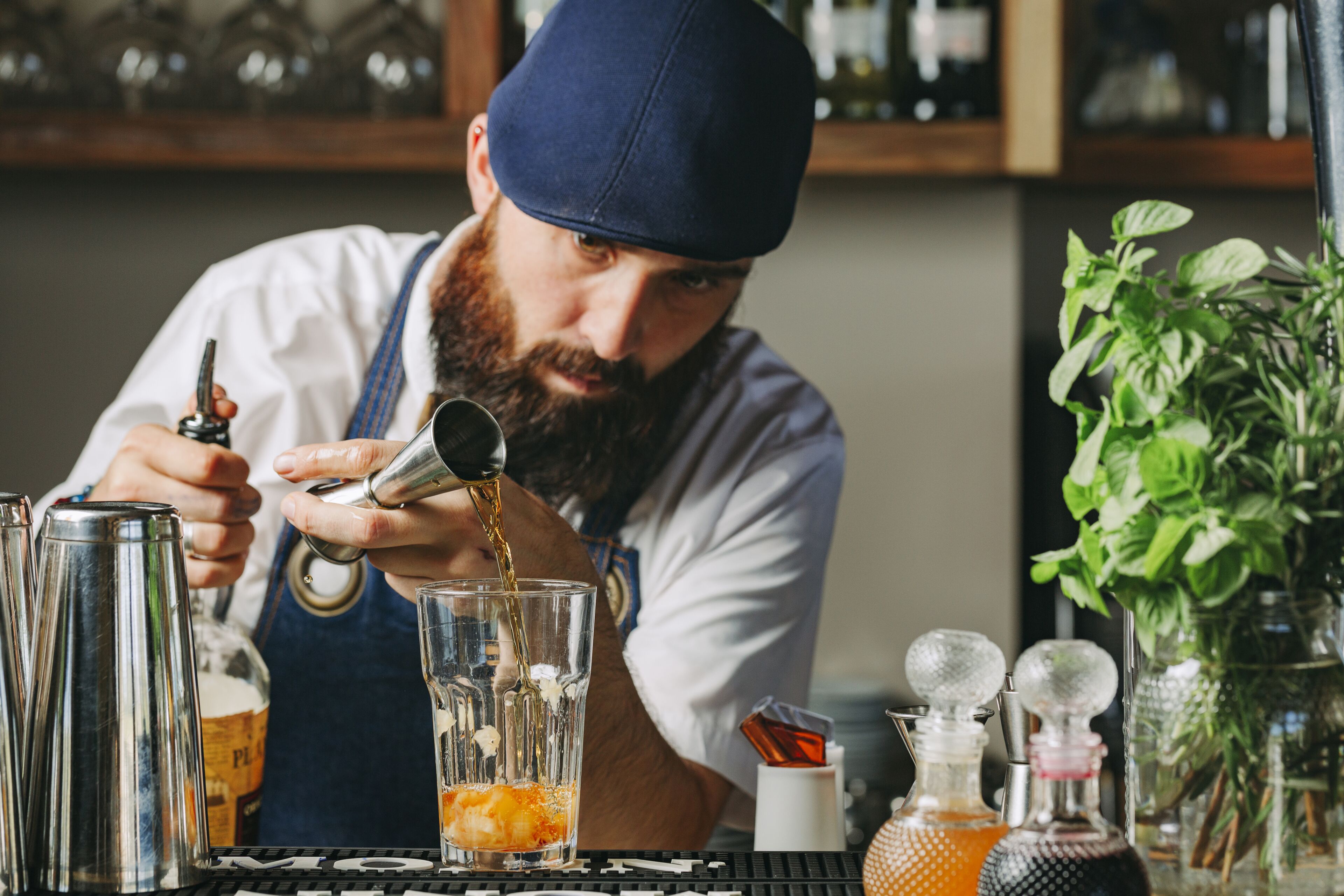 Um bartender servindo uma bebida num copo.