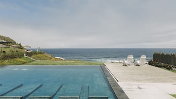 Una piscina al aire libre, sillones reclinables de piscina