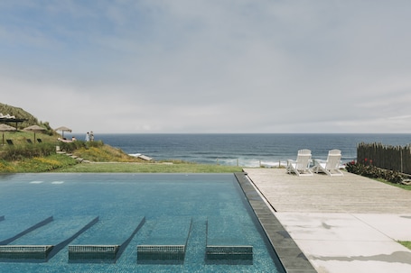 Una piscina al aire libre, sillones reclinables de piscina