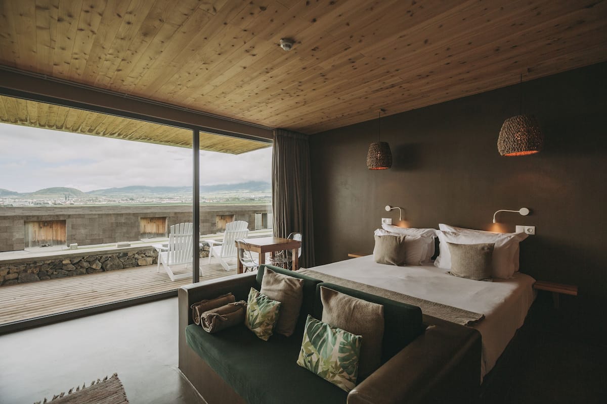 Een moderne slaapkamer met een groot bed, een sofa en uitzicht op de stad en bergen.