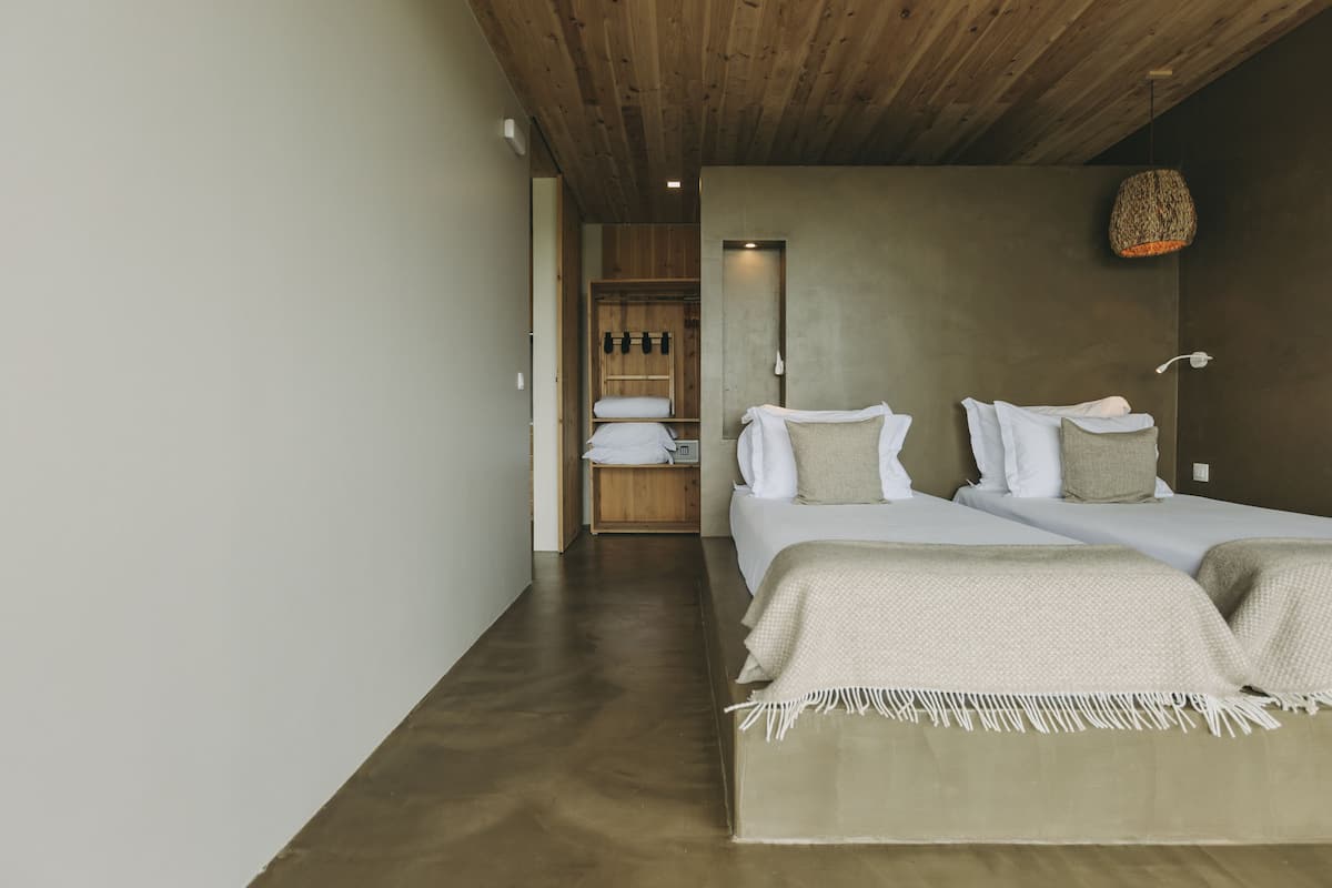 Een moderne slaapkamer met twee bedden, een houten plafond en een inbouwkast.
