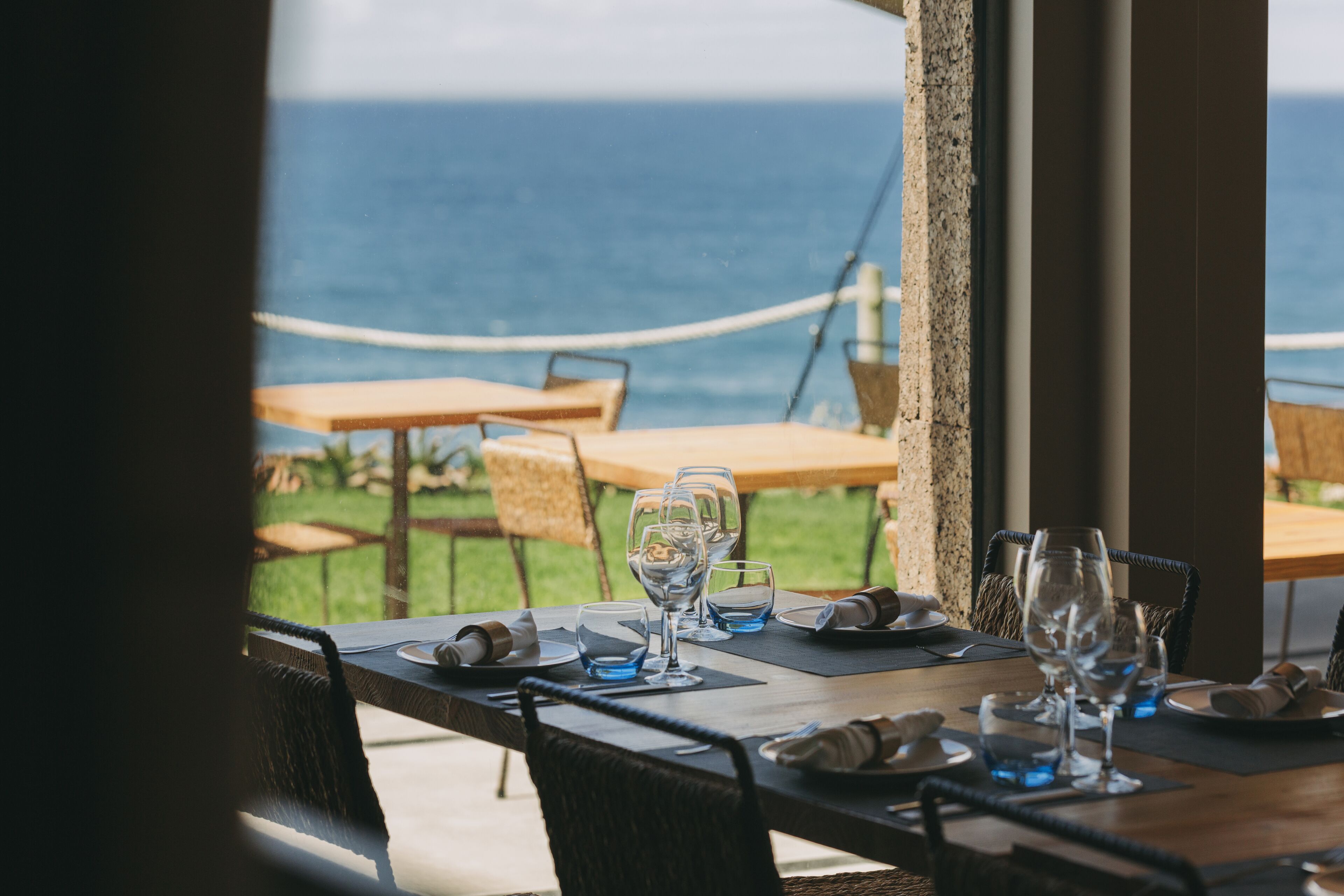 A table set for dining with a view of the ocean.