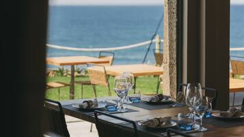 A table set for dining with a view of the ocean.
