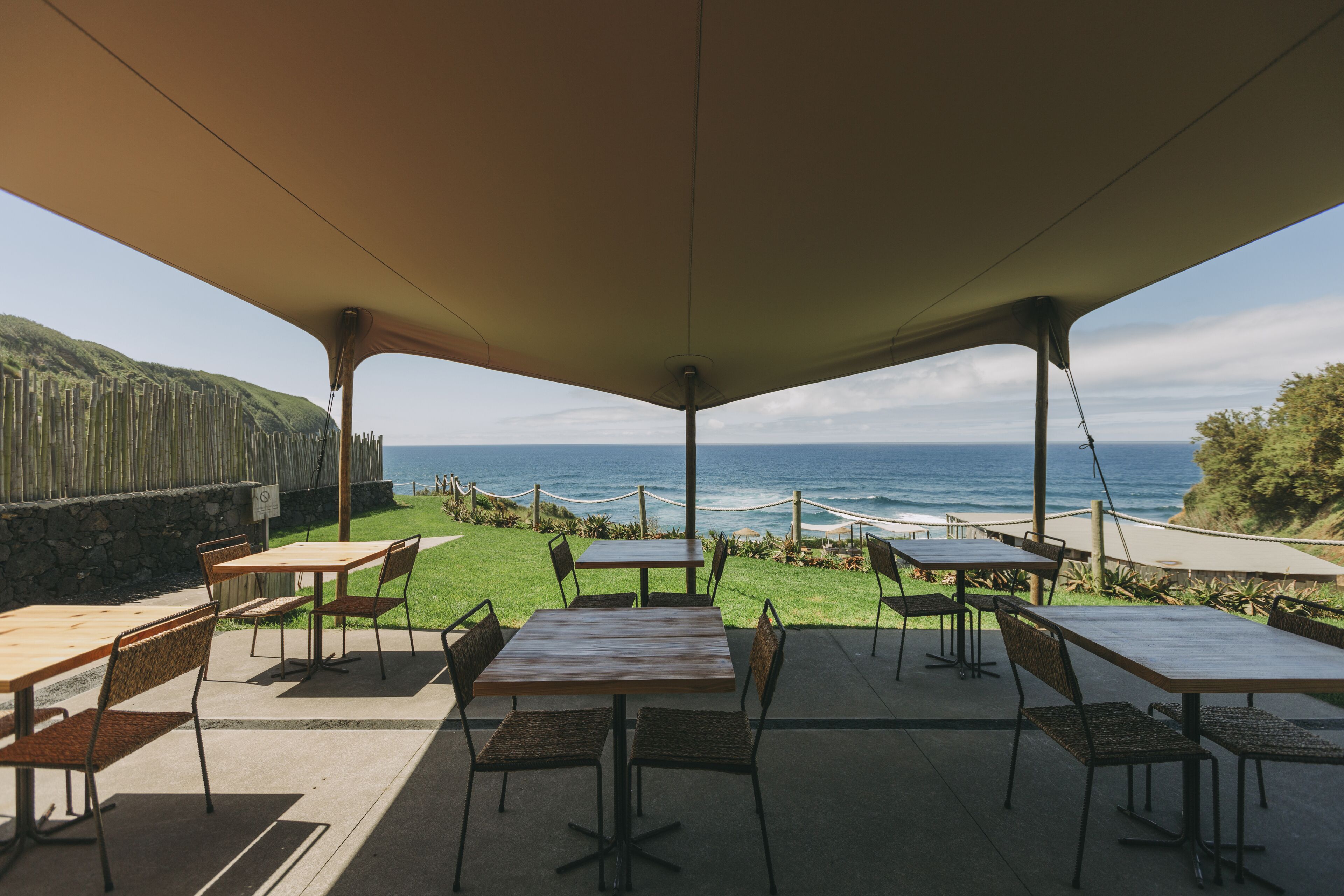 An outdoor patio with tables and chairs, overlooking a coastal view.