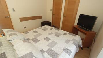 Un dormitorio con una cama, un televisor sobre un mueble bajo y un armario.