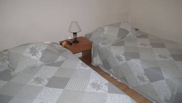 Una habitación pequeña y sencilla con dos camas, una mesita de noche y una lámpara.
