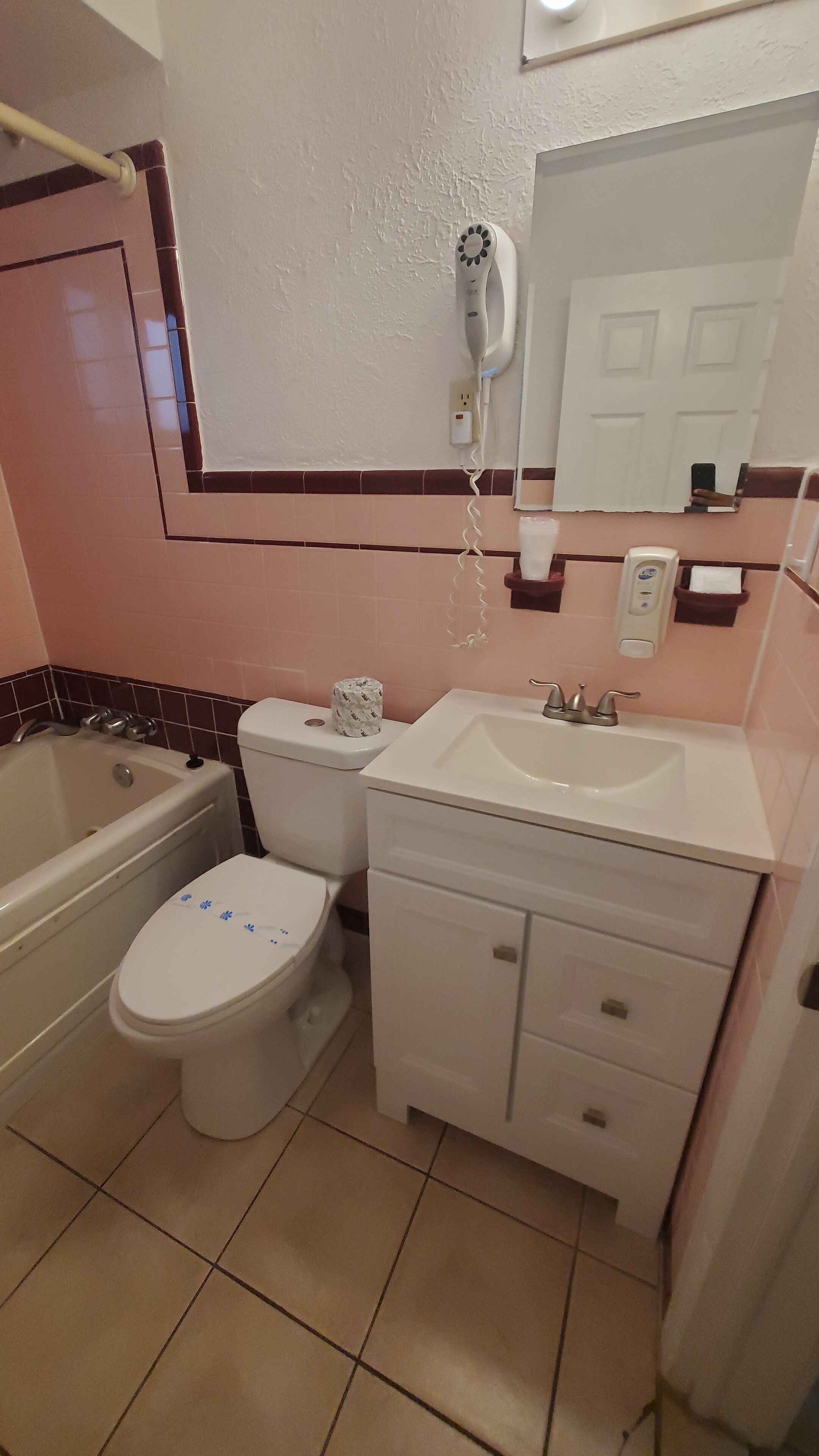 A bathroom with a bathtub, toilet, sink, and a hairdryer mounted on the wall.