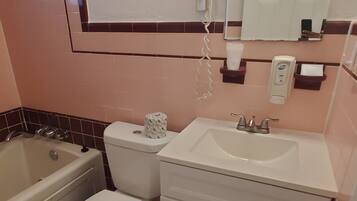A bathroom with a bathtub, toilet, sink, and a hairdryer mounted on the wall.