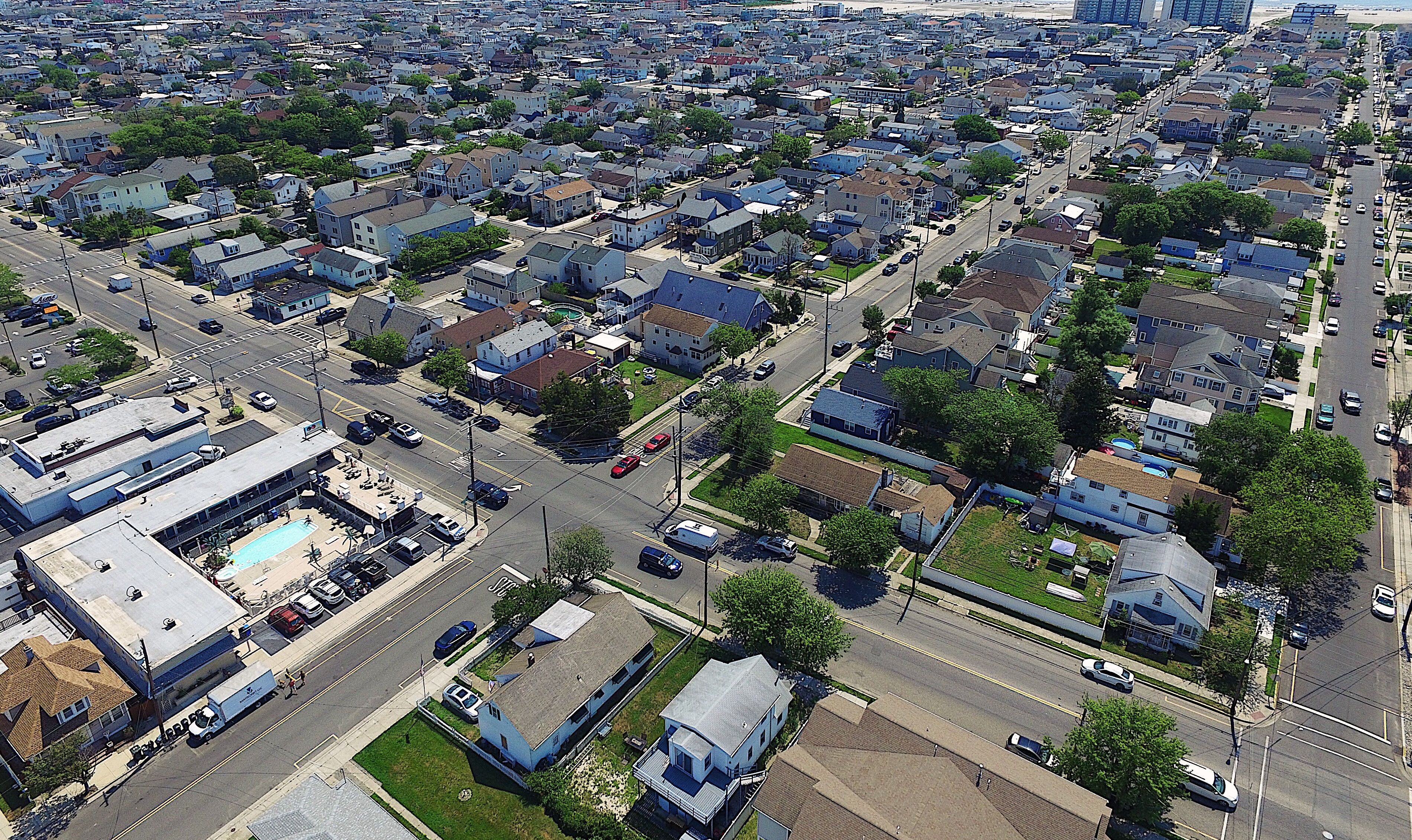 An aerial view of a residential neighborhood with houses, streets, and a commercial building with a parking lot.