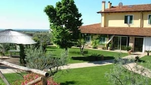 A two-story house with a garden, a patio with a table and chairs, and a large tree. - La Meridiana (Lanuvio)