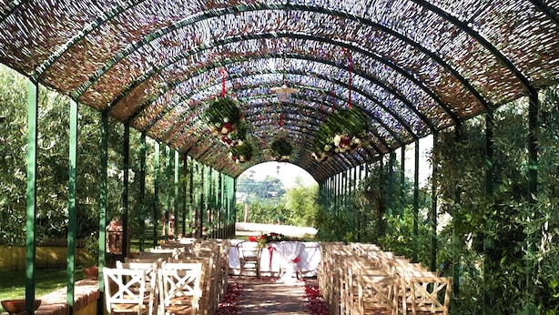 An outdoor wedding aisle with wooden chairs and a floral archway. - La Meridiana (Lanuvio)