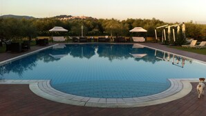 A rectangular swimming pool with a tiled edge, surrounded by lounge chairs and umbrellas. - La Meridiana (Lanuvio)